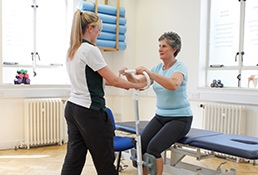 Experienced Liverpool OT helps patient stand up using physical aid.